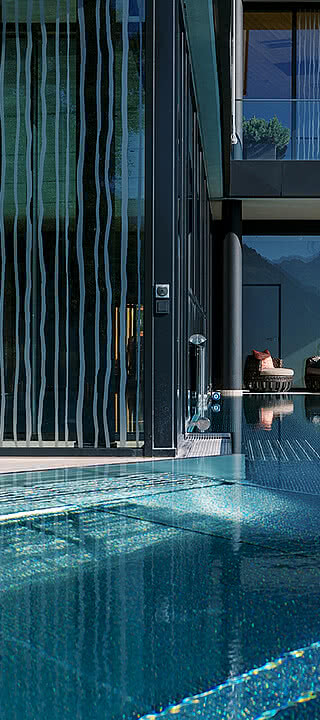 Moderne Glasarchitektur grenzt an einen ruhigen Außenpool. Eine Person entspannt auf einer Liege. Berglandschaft reflektiert im Wasser, sonnige Atmosphäre schafft eine friedliche Umgebung.