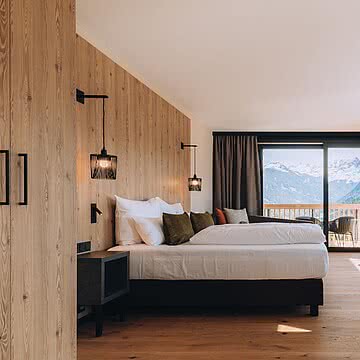 Ein Zimmer, das Raum lässt für Gespräche, für Stille, für gemeinsame Momente. Warmes Holz, weiche Stoffe und dieser Ausblick auf die Berge, der den Alltag ganz leise in den Hintergrund rückt.